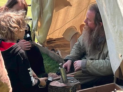 Reenactor demonstrating coin-die to child and parent
